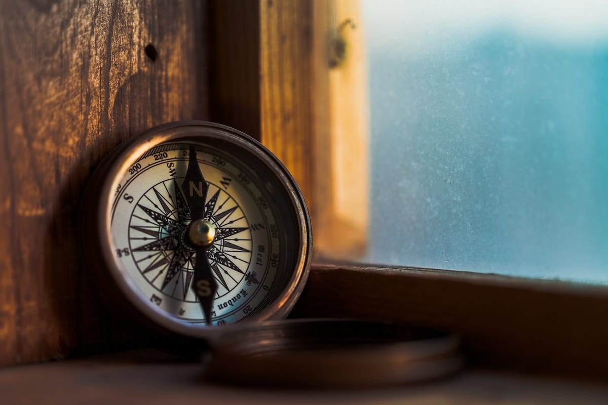 Gold compass sitting on a wooden window sill.